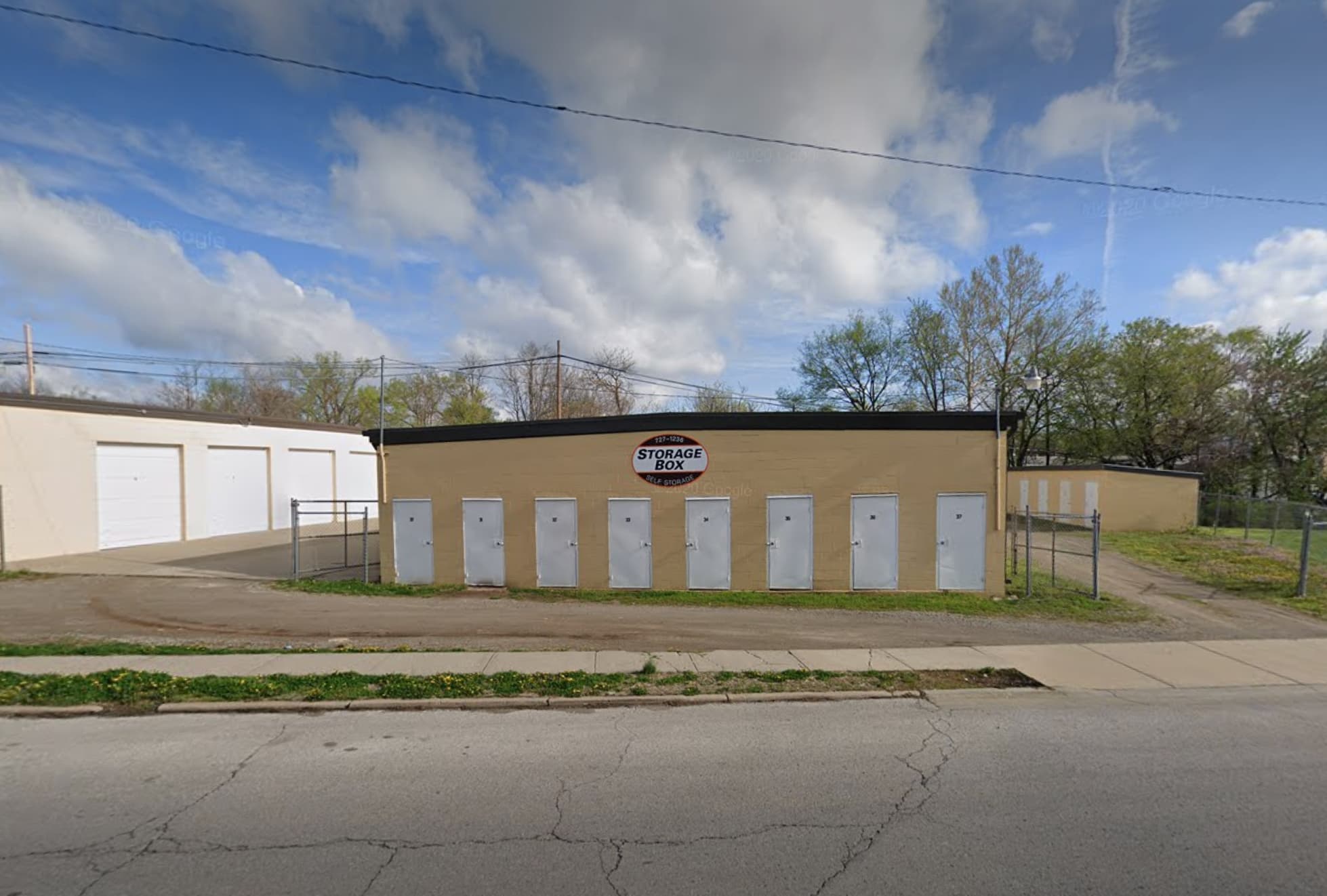 Storage Box self-storage facility featuring a yellow building with a row of white doors.