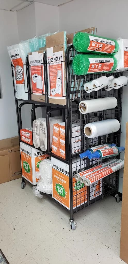 Black rolling rack stocked with moving supplies like bubble wrap, stretch film, and packing kits.